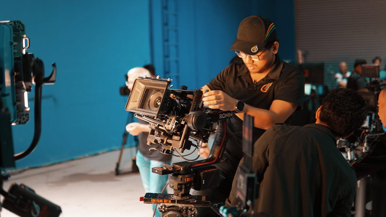 hero-img-01 Film crew setting up professional camera equipment in a studio for shooting.